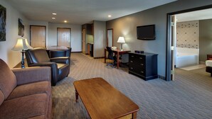 A hotel room with a seating area, a desk, a television, and a bed. - The Niobrara Lodge (Valentine)