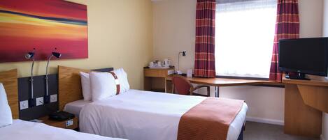 A hotel room with two beds, a desk, a television, and a painting on the wall.