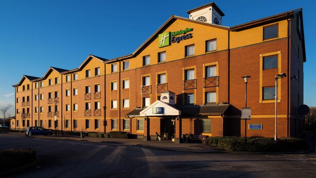 A Holiday Inn Express hotel with a brick facade, multiple windows, and a clear sky. - Holiday Inn Express Stoke On Trent by IHG (Stoke-on-Trent)