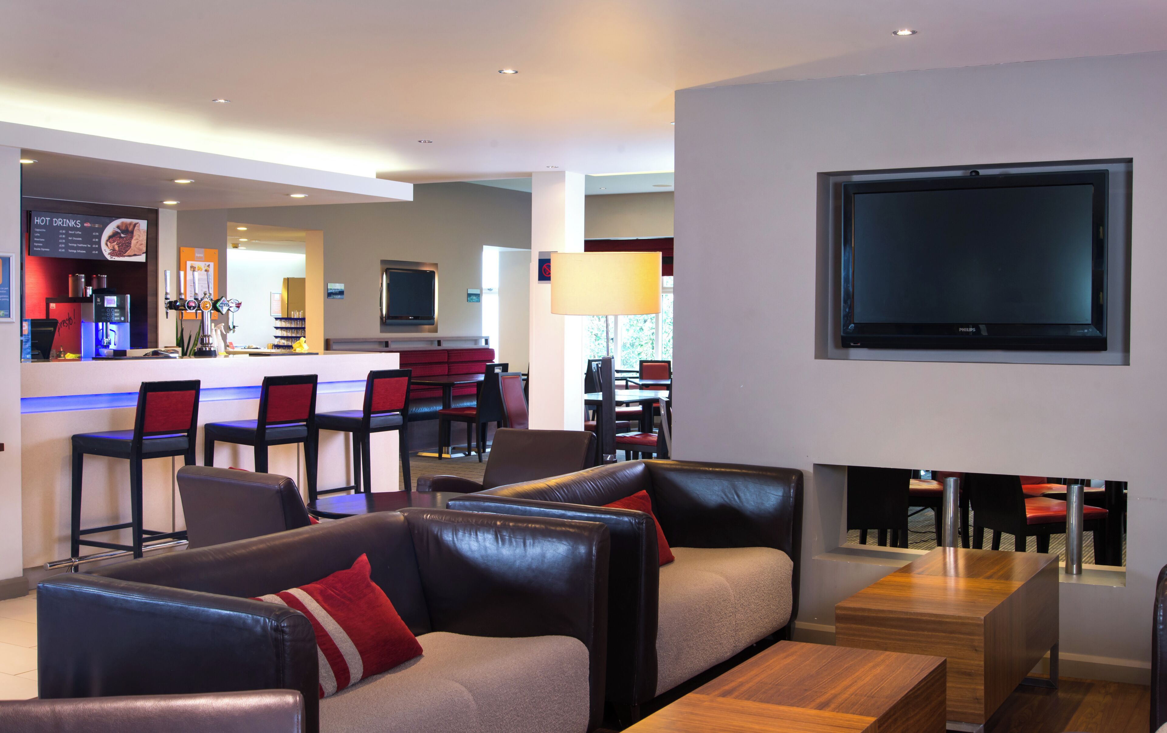 En modern hotellobby med en bardisk, sittplatser, en platt-TV och en öppen spis.