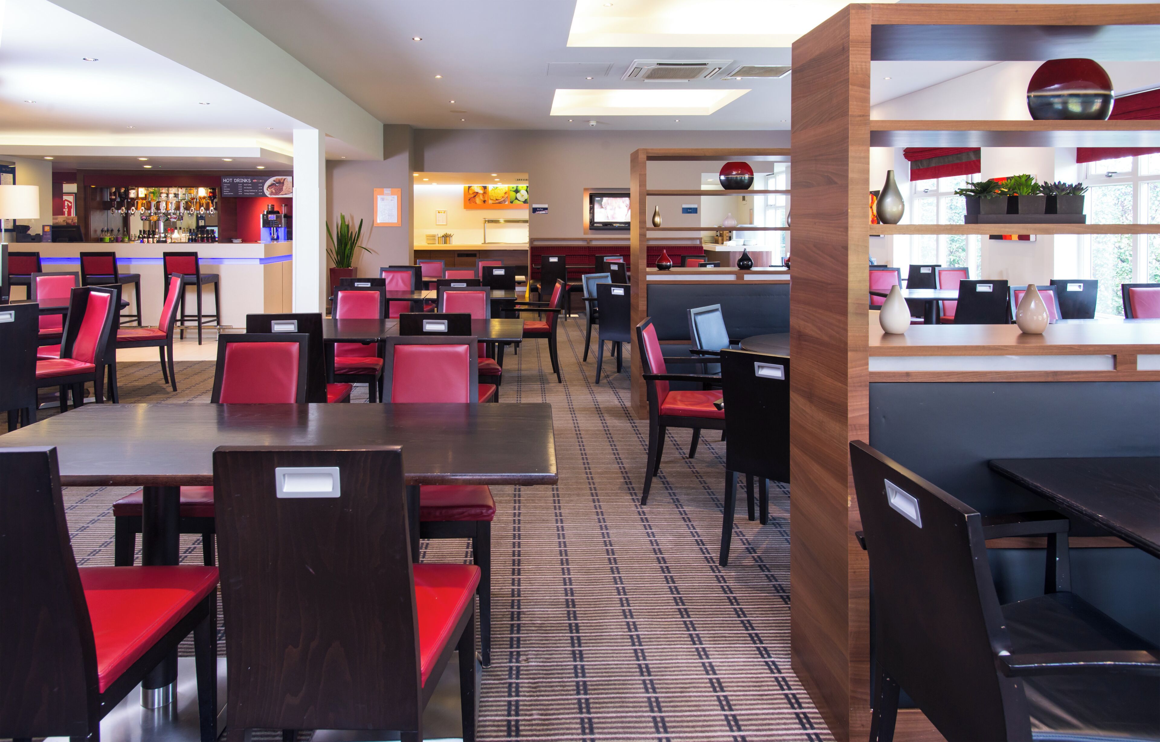 A restaurant with multiple tables and chairs, a bar area, and a counter with a menu.