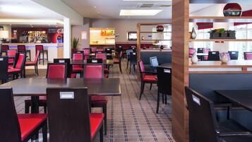 A restaurant with multiple tables and chairs, a bar area, and a counter with a menu.
