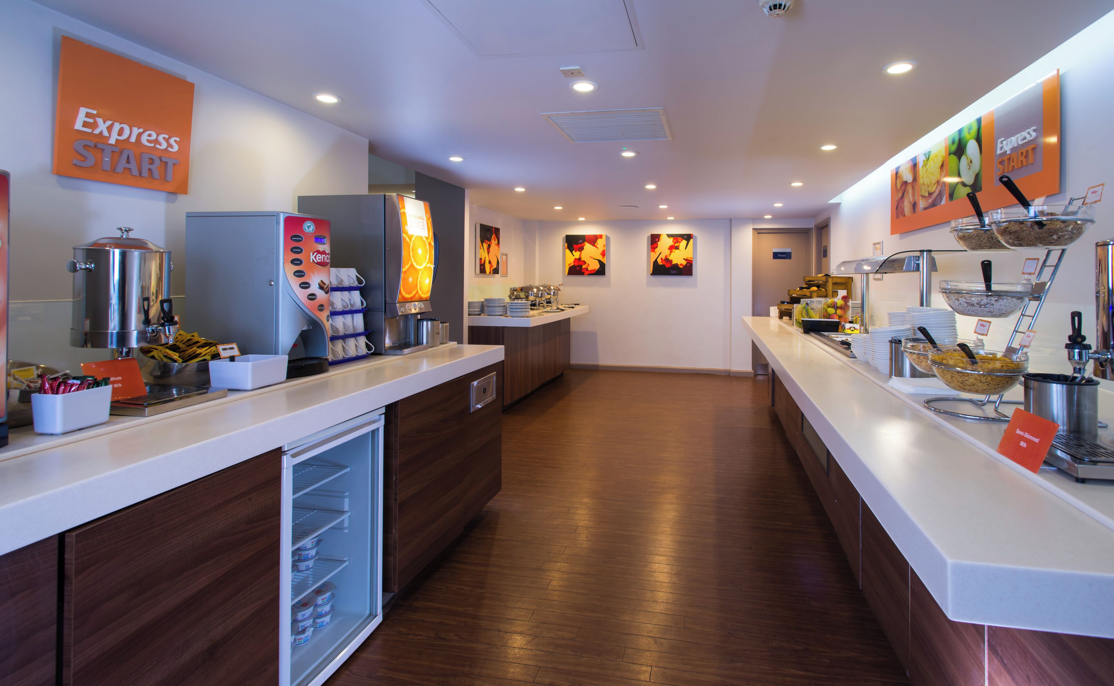 A buffet setup with a coffee machine, a refrigerator, and various food containers.