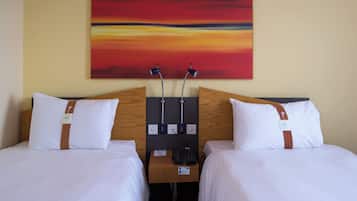 Ein Hotelzimmer mit zwei Betten, einem hölzernen Kopfteil, einem Nachttisch mit Telefon und einem Bild an der Wand.