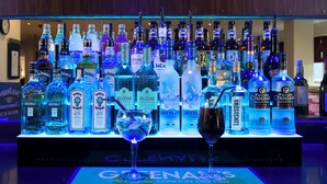 A bar with a variety of liquor bottles and a glass with a straw. - Holiday Inn Express Stoke On Trent by IHG (Stoke-on-Trent)