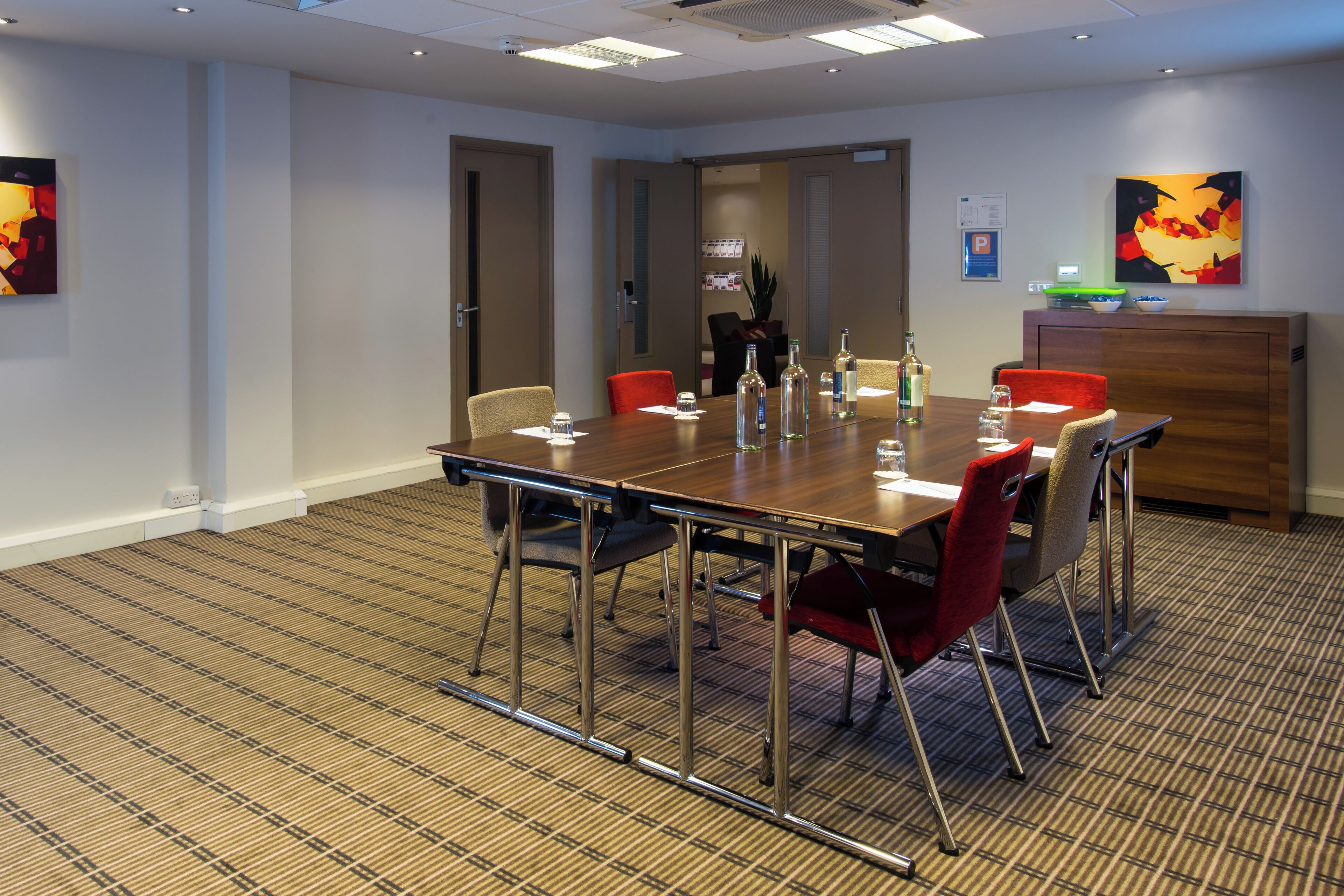 A conference room with a long table, chairs, and a wooden cabinet.