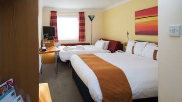 Een hotelkamer met twee bedden, een bureau, een televisie, een telefoon en een schilderij aan de muur.