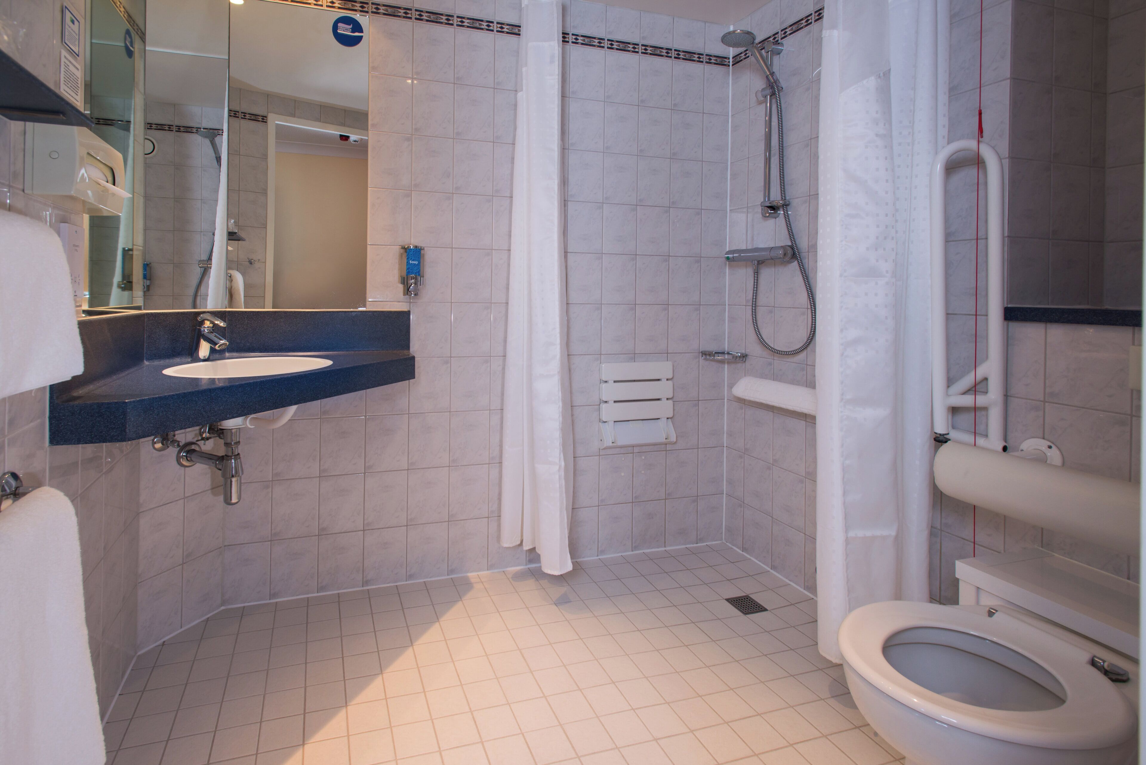Un baño con lavamanos, inodoro, ducha y espejo.