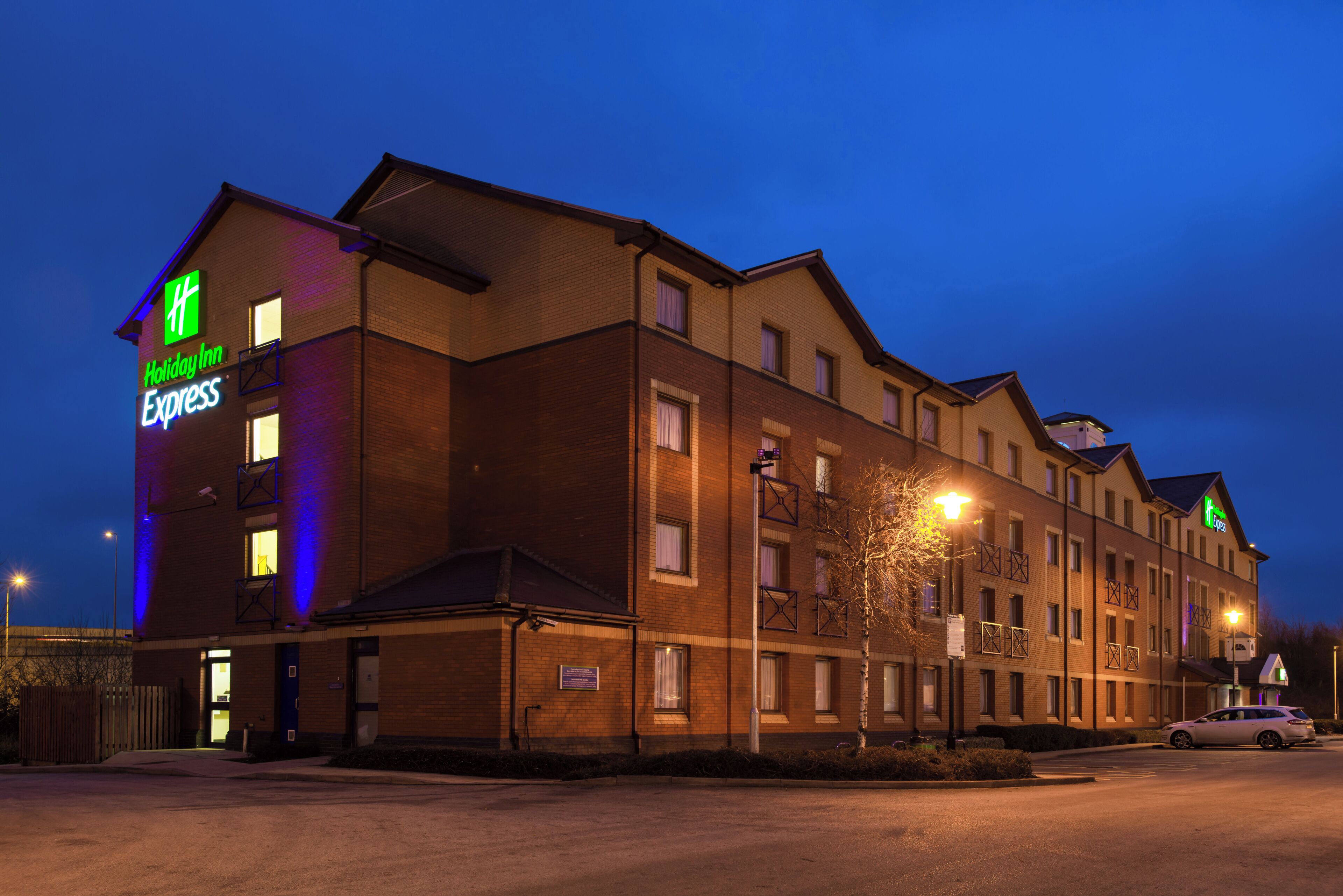 Un hôtel Holiday Inn Express avec une façade en briques, de nombreuses fenêtres et un parking.