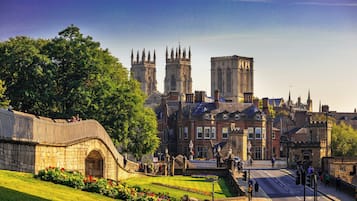 A historic building with a prominent tower, a stone bridge, and a well-maintained garden.