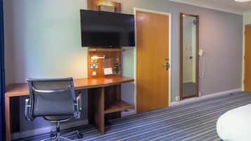 Une chambre d’hôtel équipée d’un bureau, d’une chaise, d’une télévision et d’une porte.