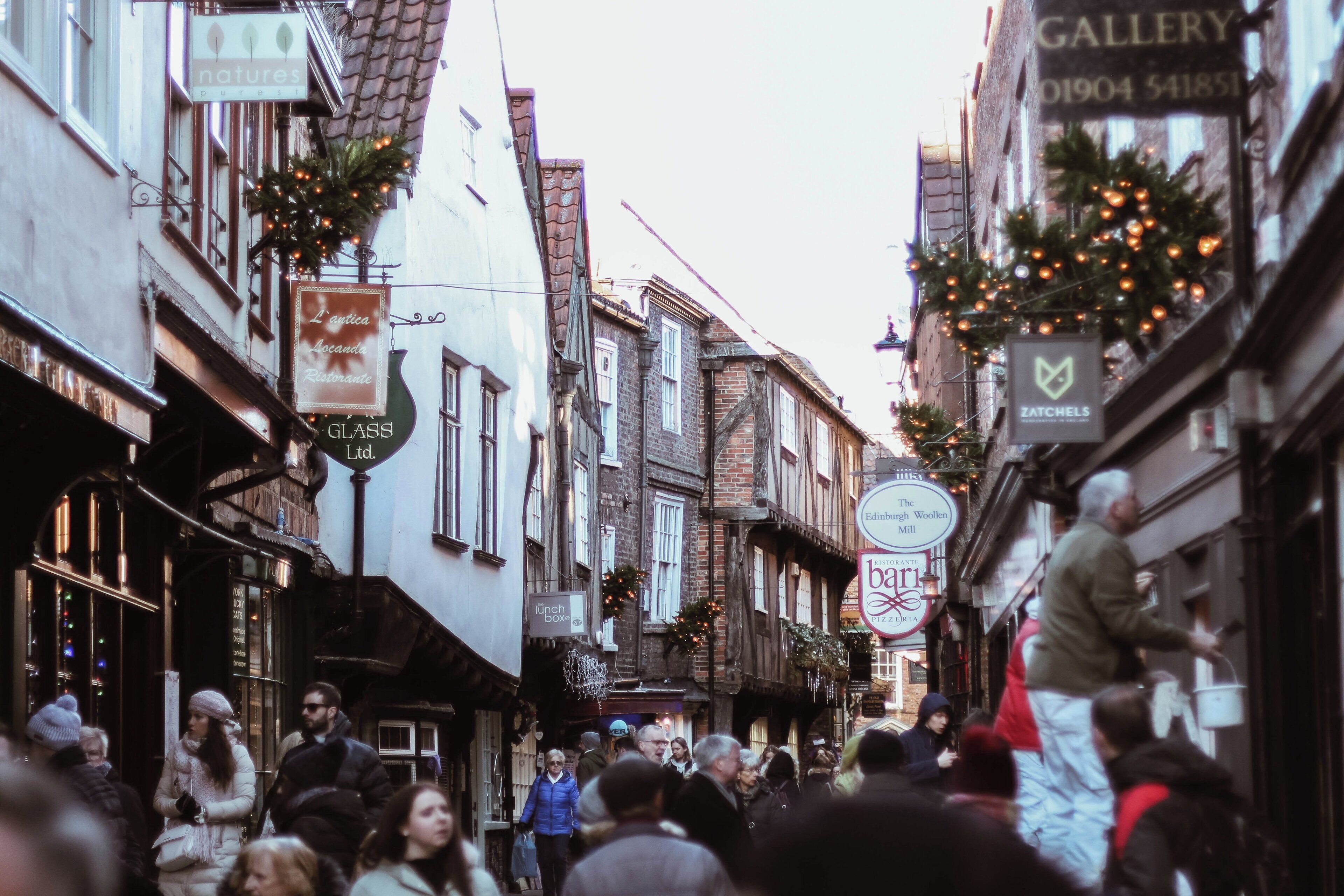 Une rue étroite bordée de bâtiments traditionnels, dont certains arborent des enseignes indiquant la présence de commerces locaux.