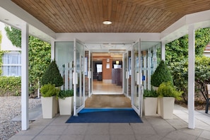 A modern building entrance with glass doors, a wooden ceiling, and potted plants. - Holiday Inn Express York by IHG (York)