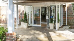A building entrance with glass doors, a brick wall, and potted plants. - Holiday Inn Express York by IHG (York)