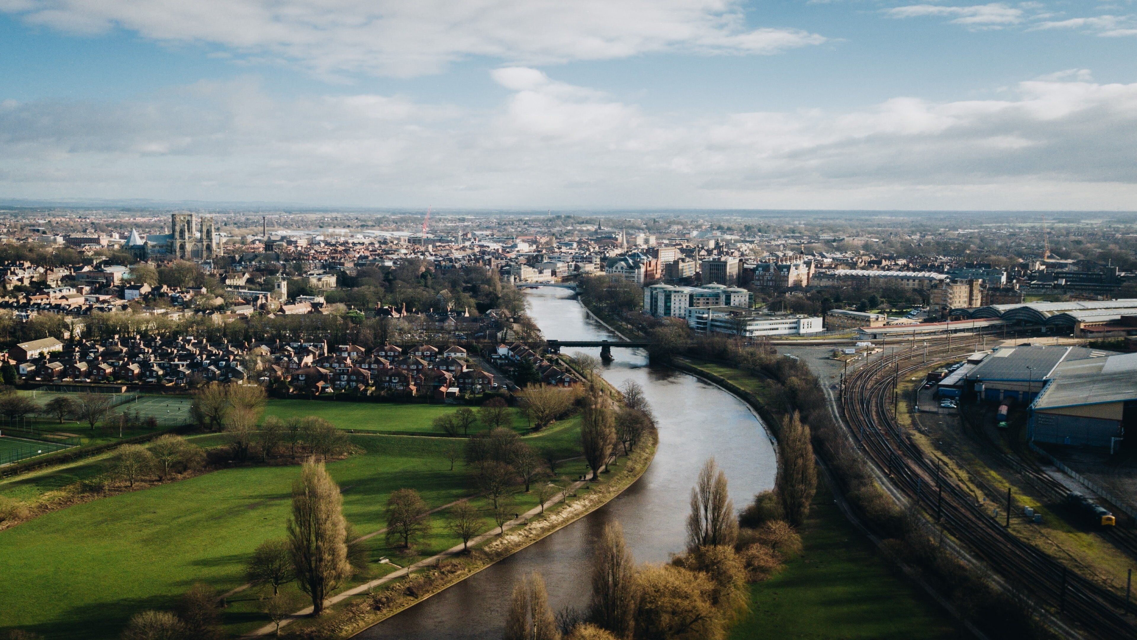 A river flowing through a city with a bridge, buildings, and green spaces.
