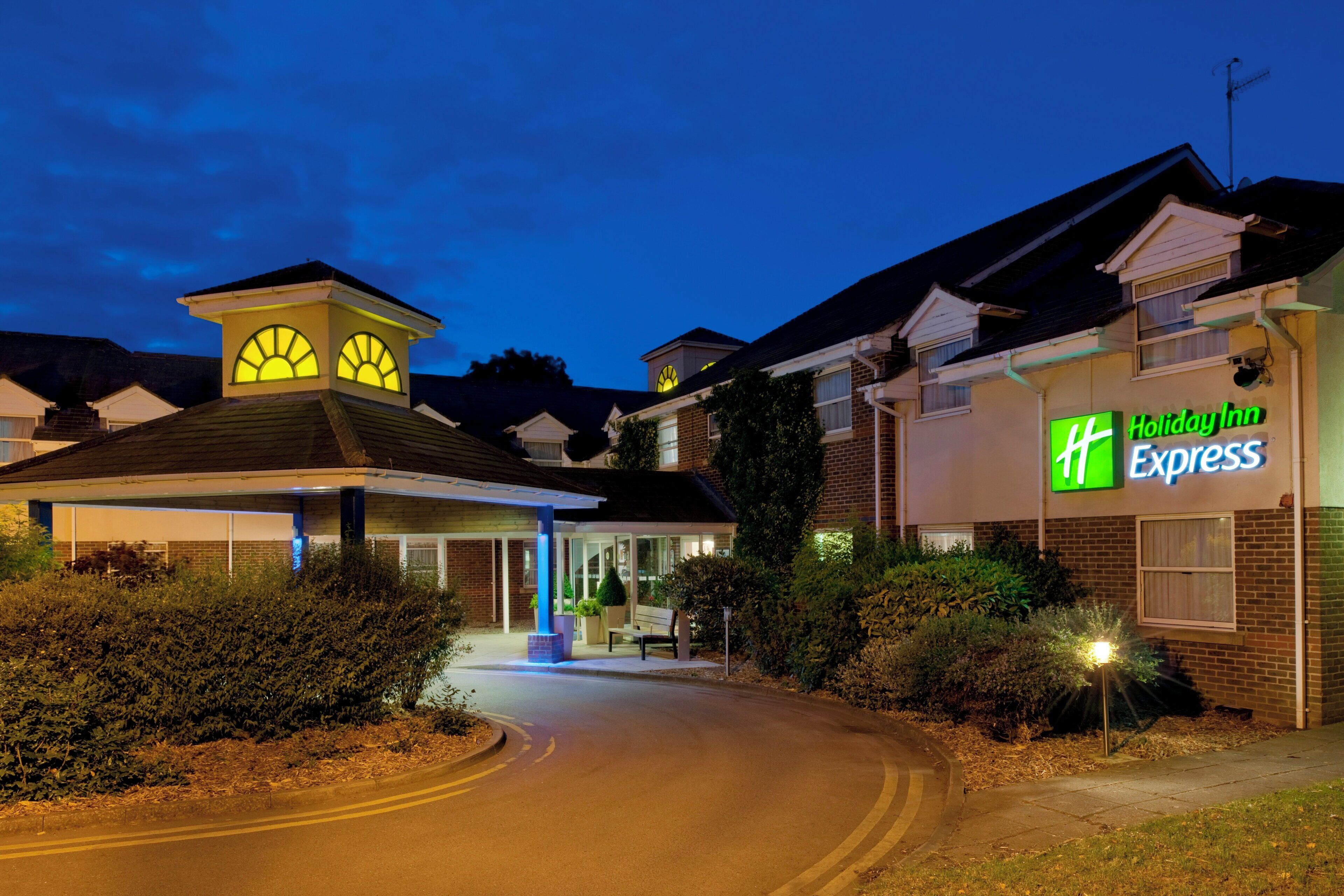 Et Holiday Inn Express hotel med overdækket indgang og synlig parkeringsplads.
