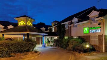 Et Holiday Inn Express hotel med overdækket indgang og synlig parkeringsplads.