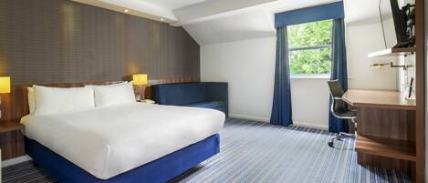 A hotel room with a large bed, a desk, and a chair.