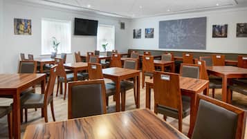 A conference room with multiple tables and chairs, a large map on the wall, and artwork on the walls.