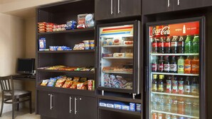 Zona de máquinas expendedoras con refrigerios, bebidas y un refrigerador.