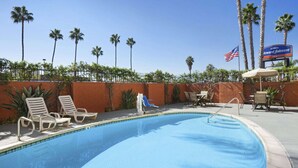 Una piscina con sillones de descanso y un letrero del Howard Johnson Inn.