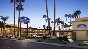 Un hotel Howard Johnson con estacionamiento, palmeras y cielo despejado.
