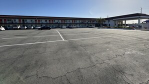 Un parcheggio con diverse auto, un motel con varie camere e una stazione di servizio con tettoia.