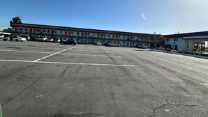 A motel with multiple rooms, a parking lot, and a clear sky. - Vivo Hotel (Stanton)