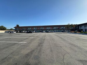 A multi-story motel with a parking lot in front.