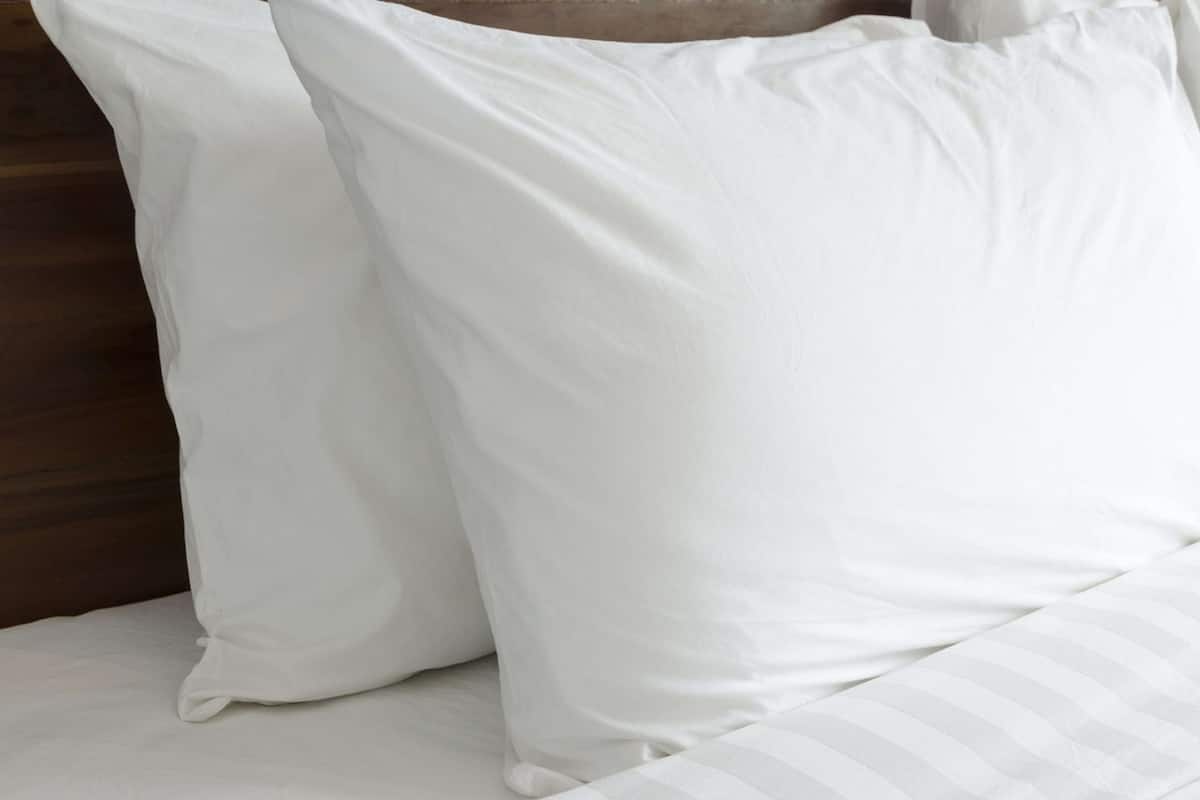 A bed with white bedding and a striped pillow.