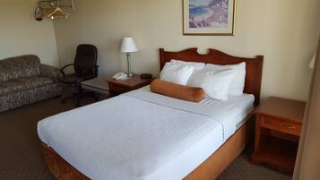 Une chambre d’hôtel avec un grand lit, un bureau avec une lampe, une chaise, un canapé et un tableau au mur.