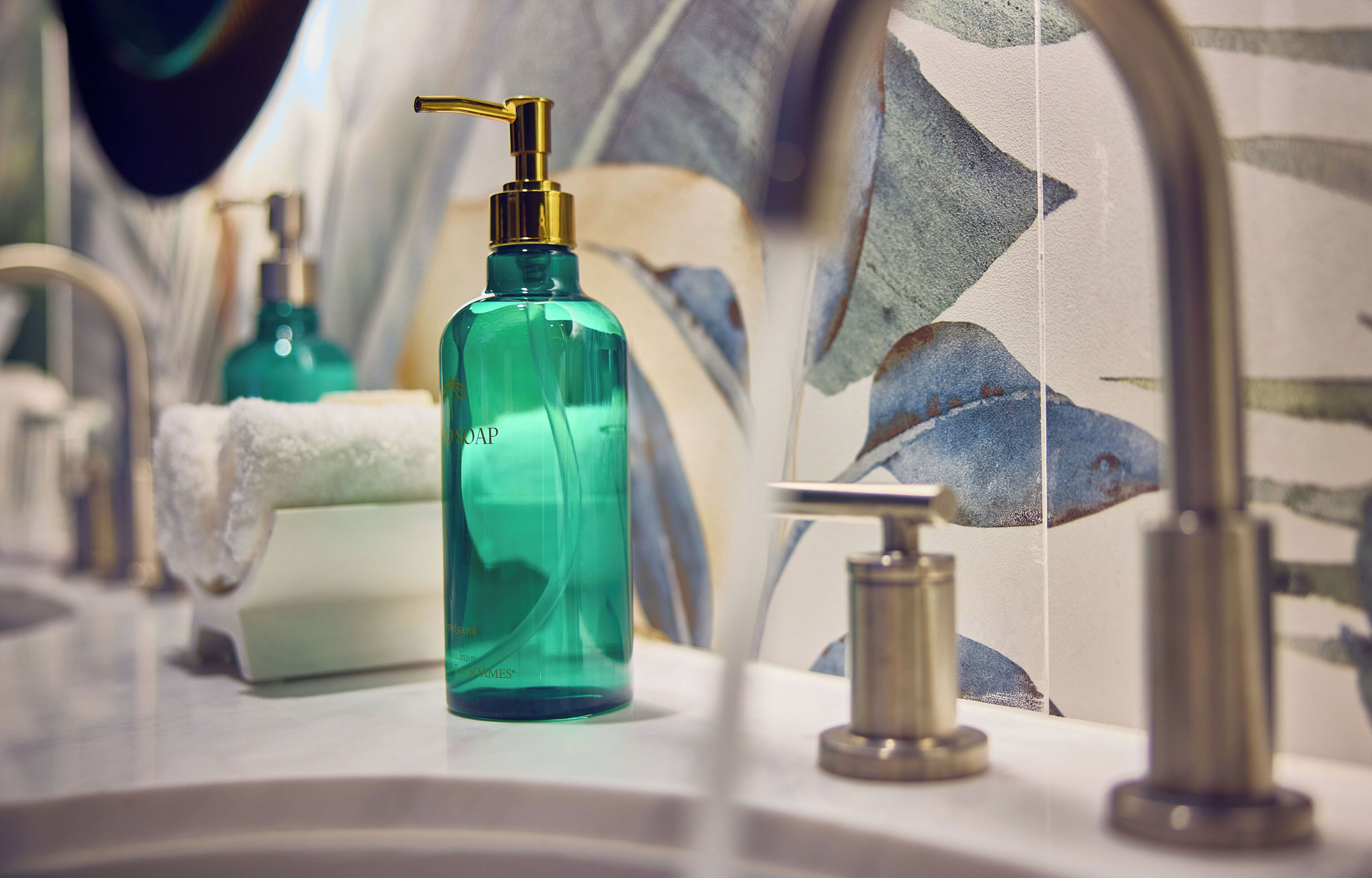 A bathroom with a modern design, featuring a sink, a green soap dispenser, and a towel.
