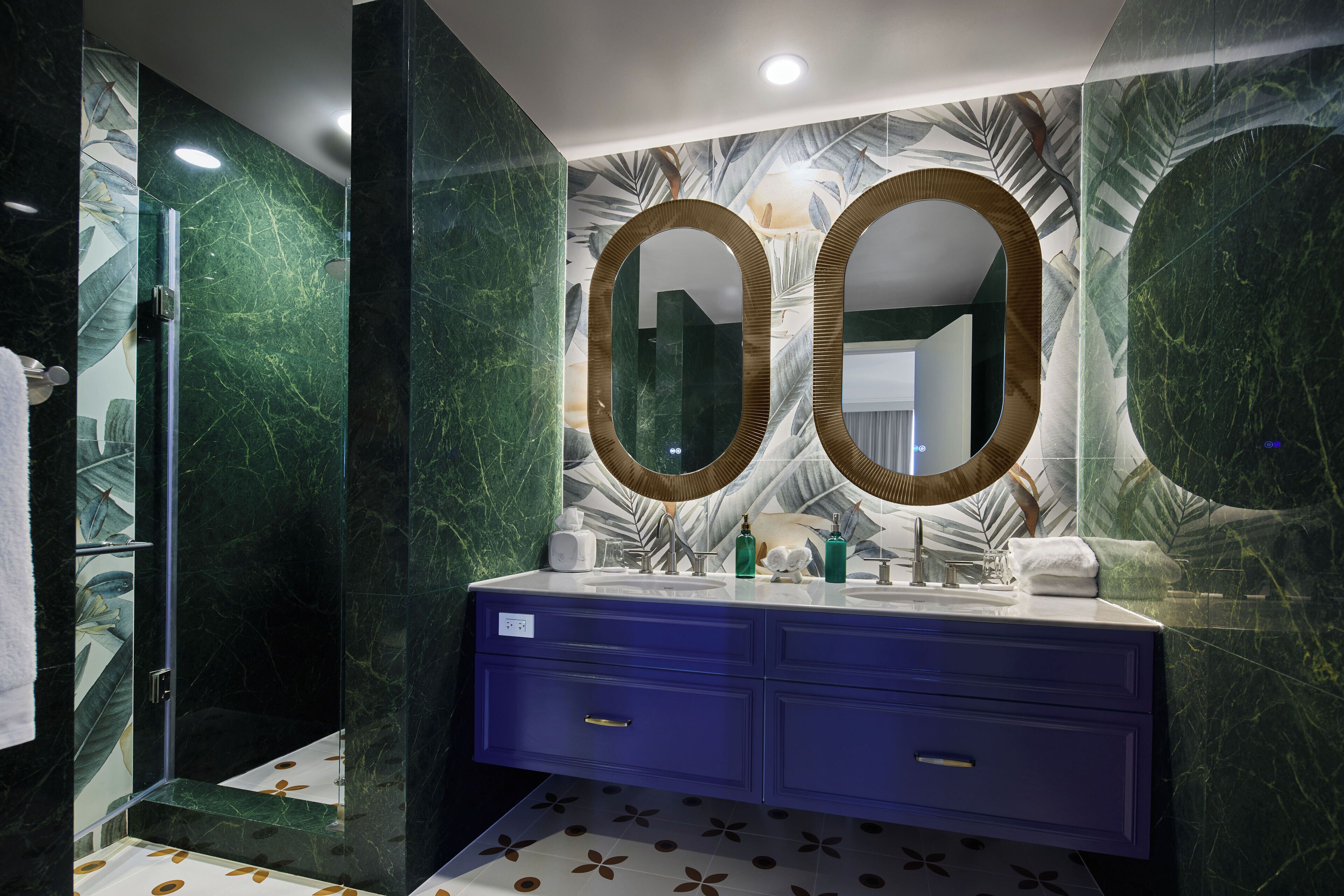 Un baño con pared de mármol, un espejo grande y un tocador azul.