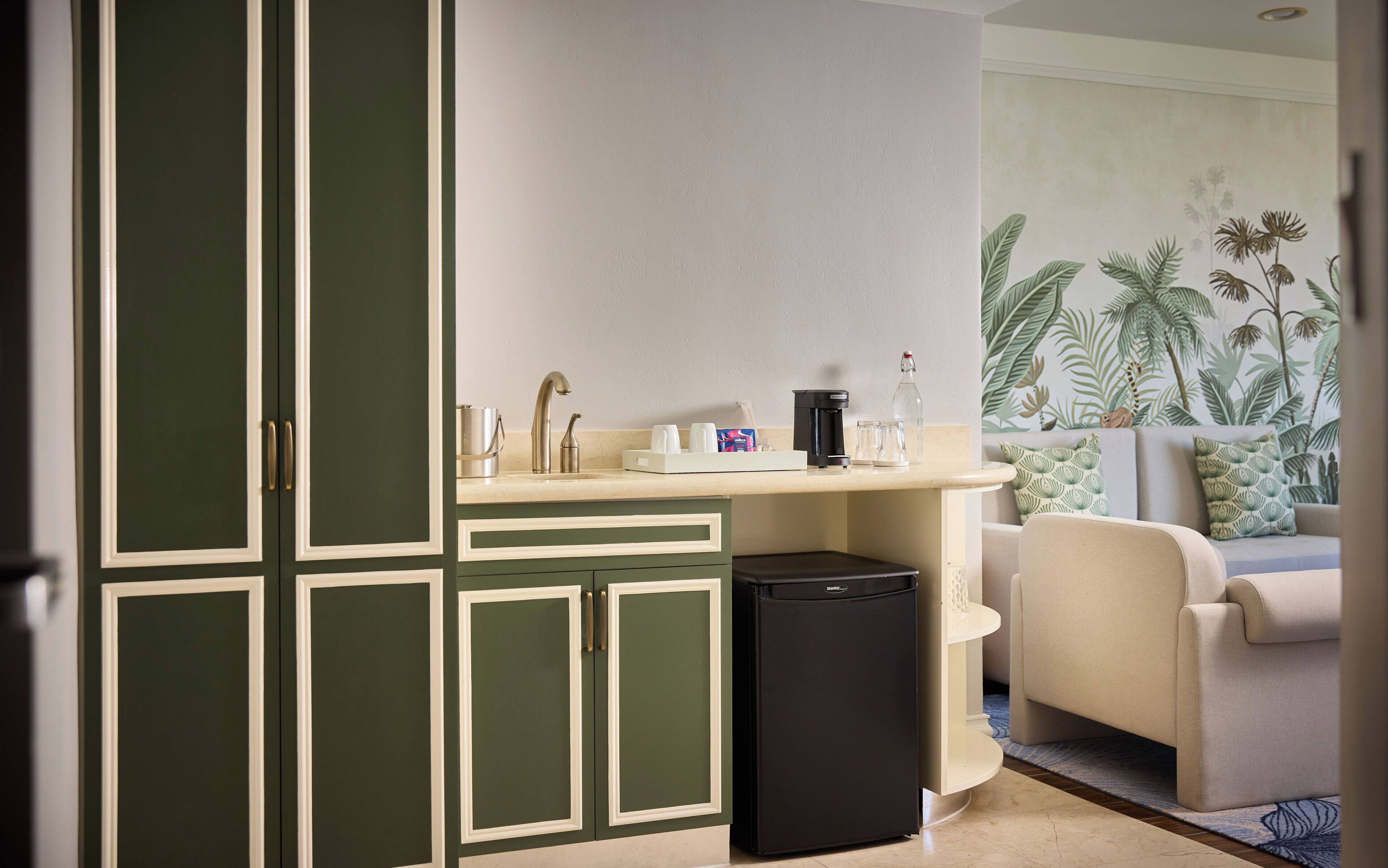 A compact kitchen with a sink, coffee maker, and storage cabinets.