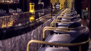 Un espace bar avec un long comptoir et des rangées de chaises.