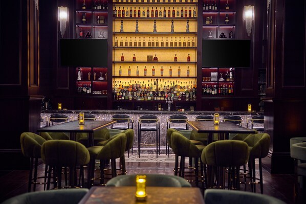 A bar area with multiple shelves of bottles, a bar counter, and several tables with chairs.