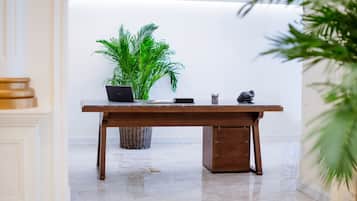 Una mesa de recepción con una computadora portátil, una planta en maceta y una pequeña estatua.