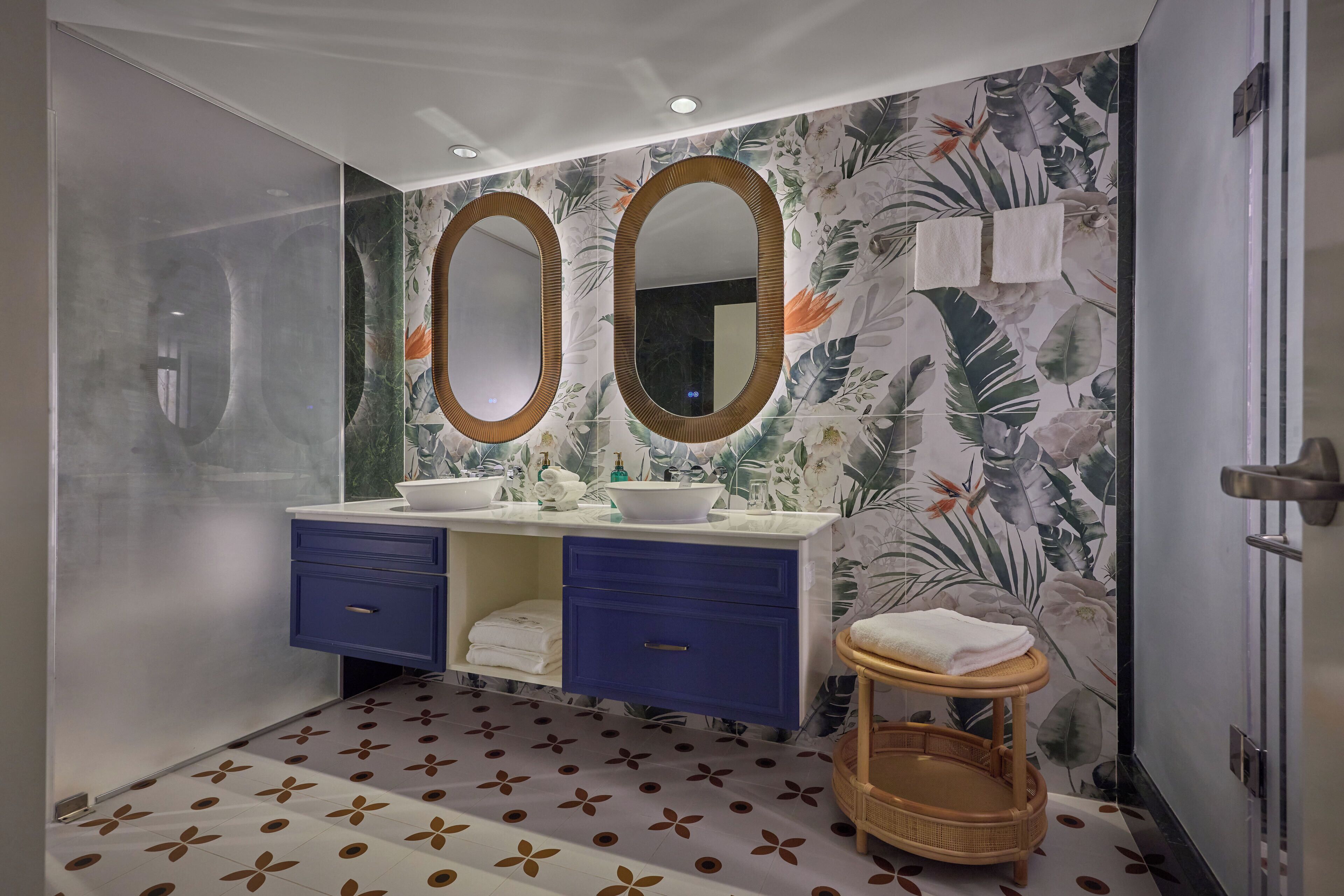 A bathroom with two sinks, a large mirror, and a decorative wall.