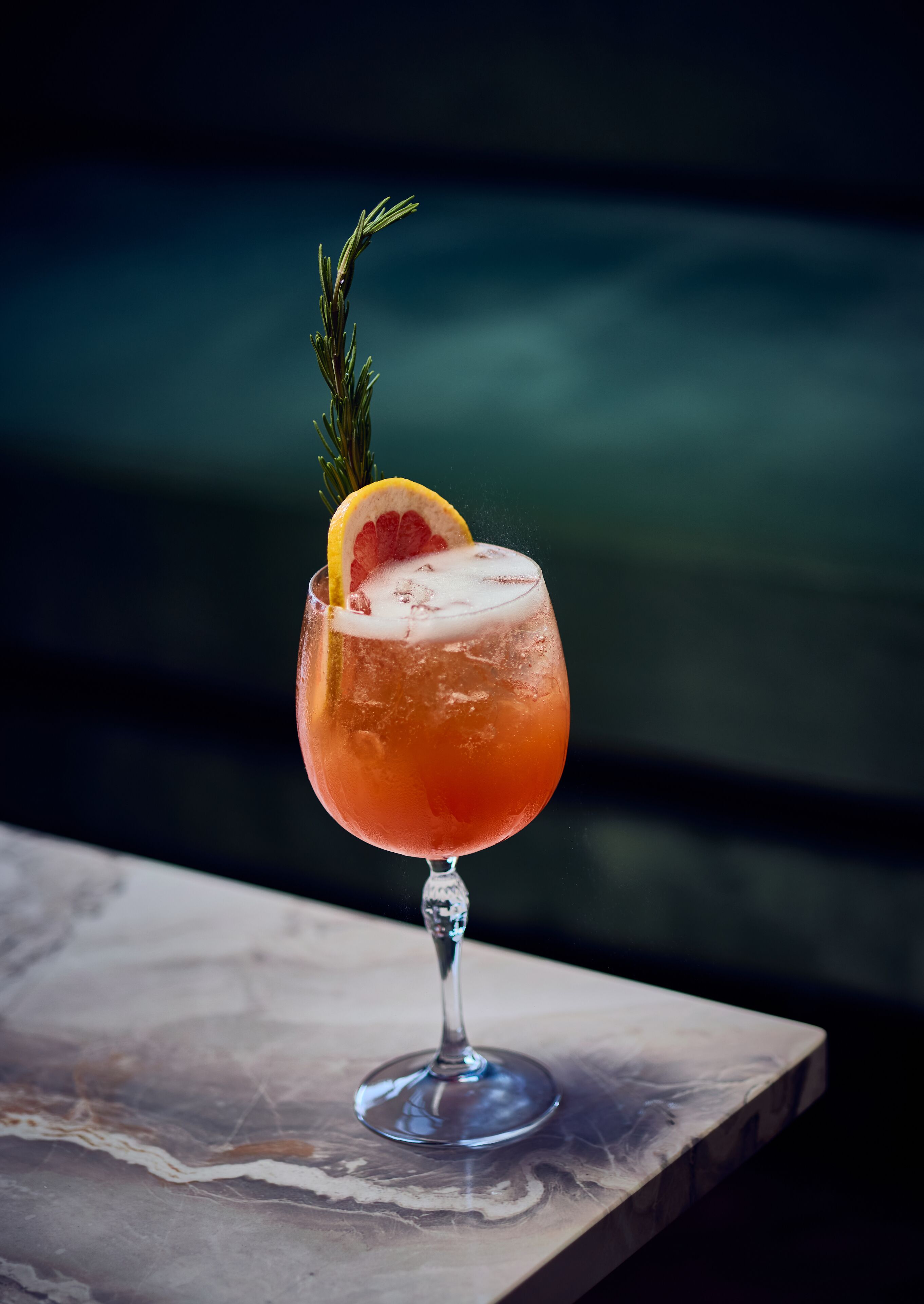Un cocktail servi dans un verre à pied, agrémenté d’une garniture, sur un fond flou.
