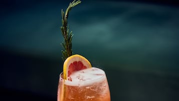 A cocktail in a stemmed glass with a garnish, set against a blurred background.