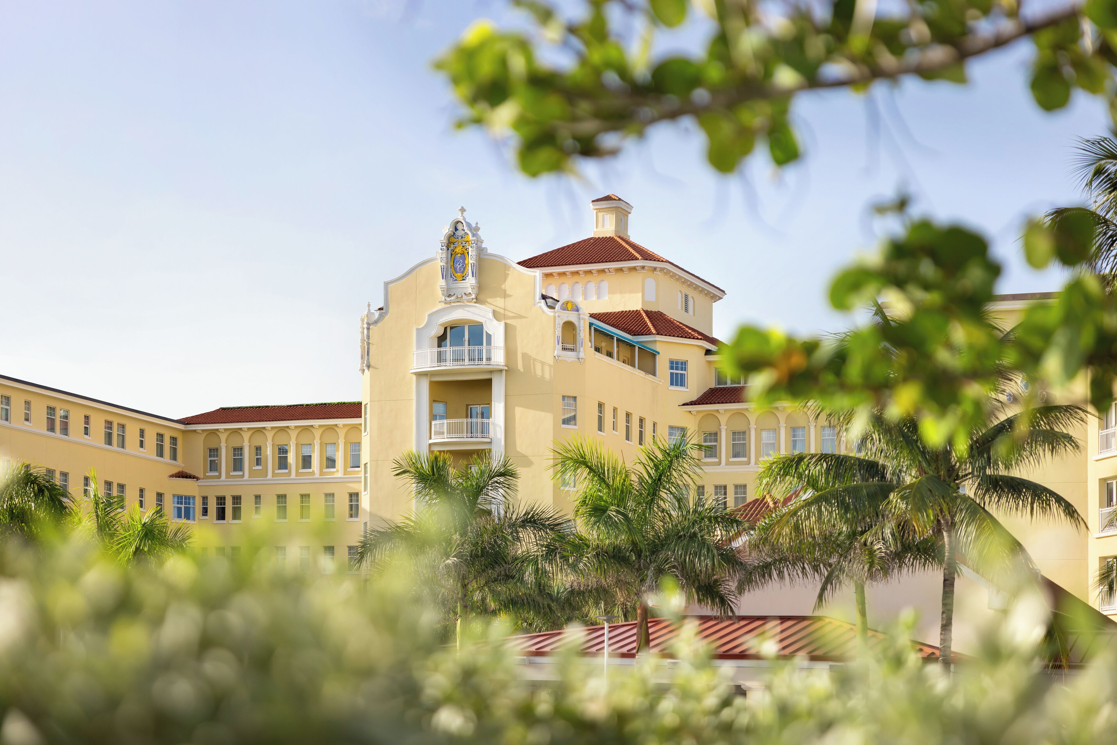 A multi-story hotel with a central tower, balconies, and a red roof.