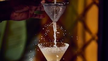 Una mano vertiendo un líquido en una copa de martini.