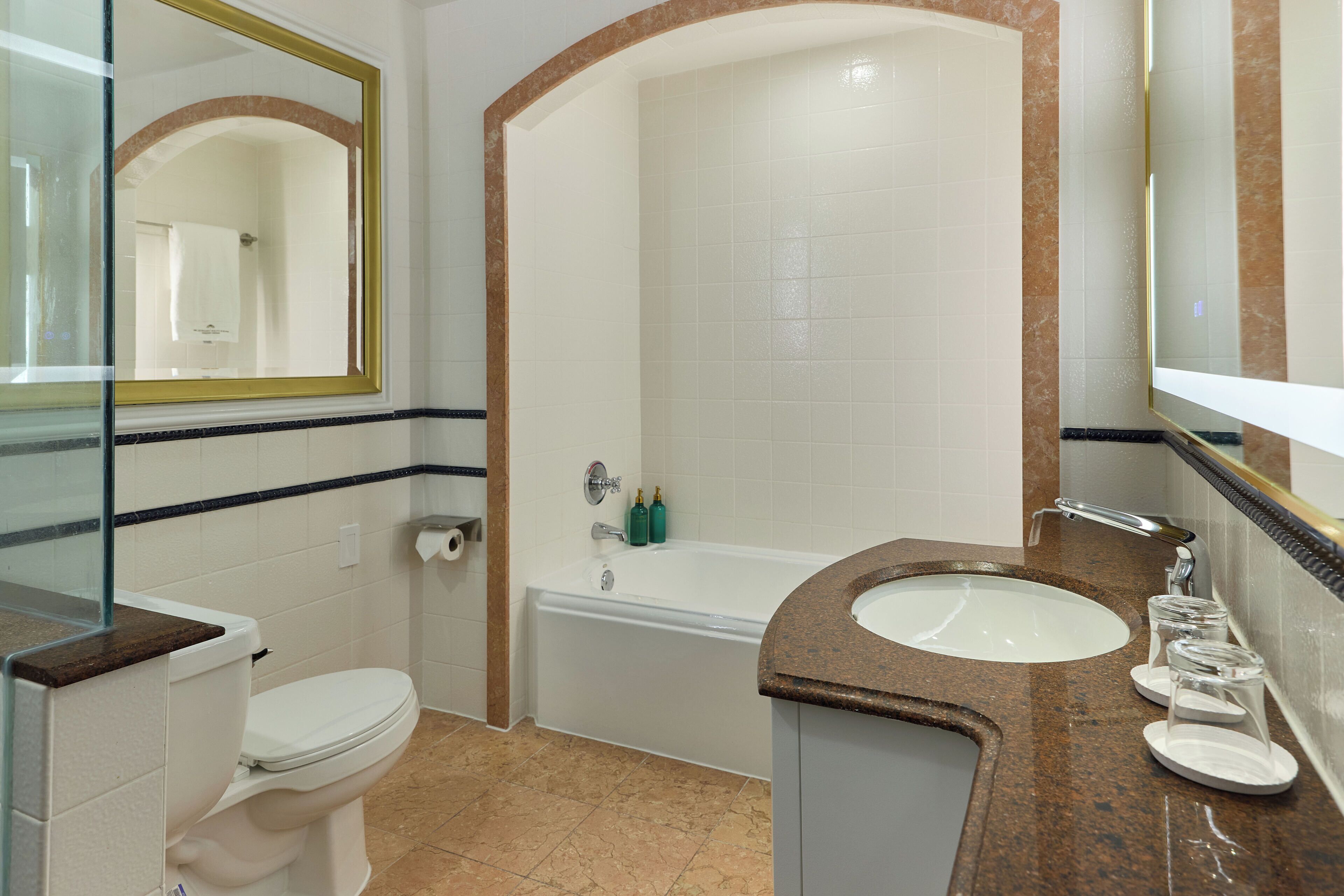 A bathroom with a toilet, a sink, a bathtub, and a mirror.