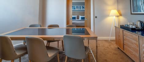 A conference room with a glass table, four chairs, a lamp, and a wooden cabinet.