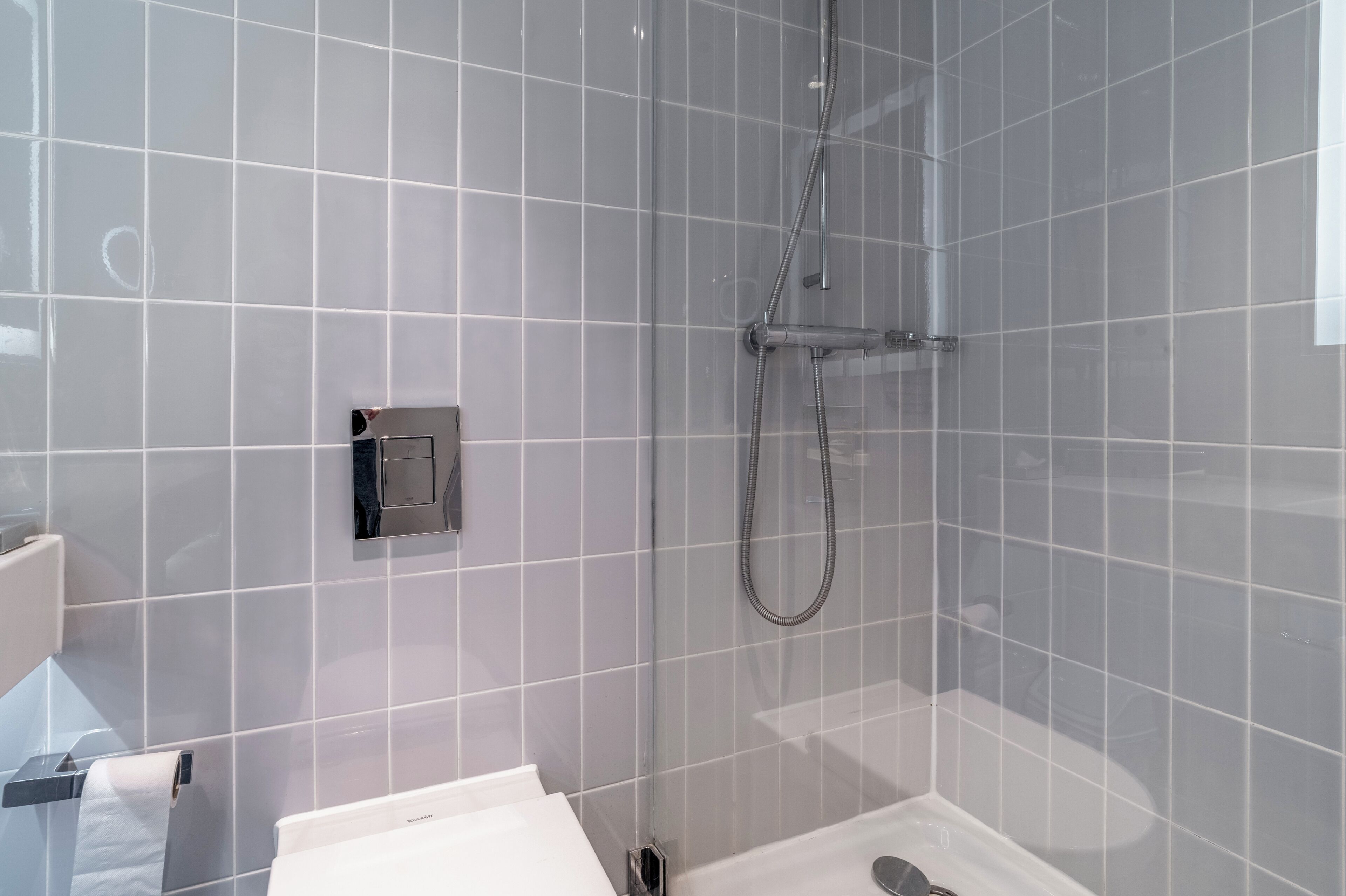 A modern bathroom with a glass shower enclosure, a toilet, and a sink.