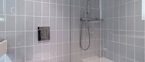 A modern bathroom with a glass shower enclosure, a toilet, and a sink.