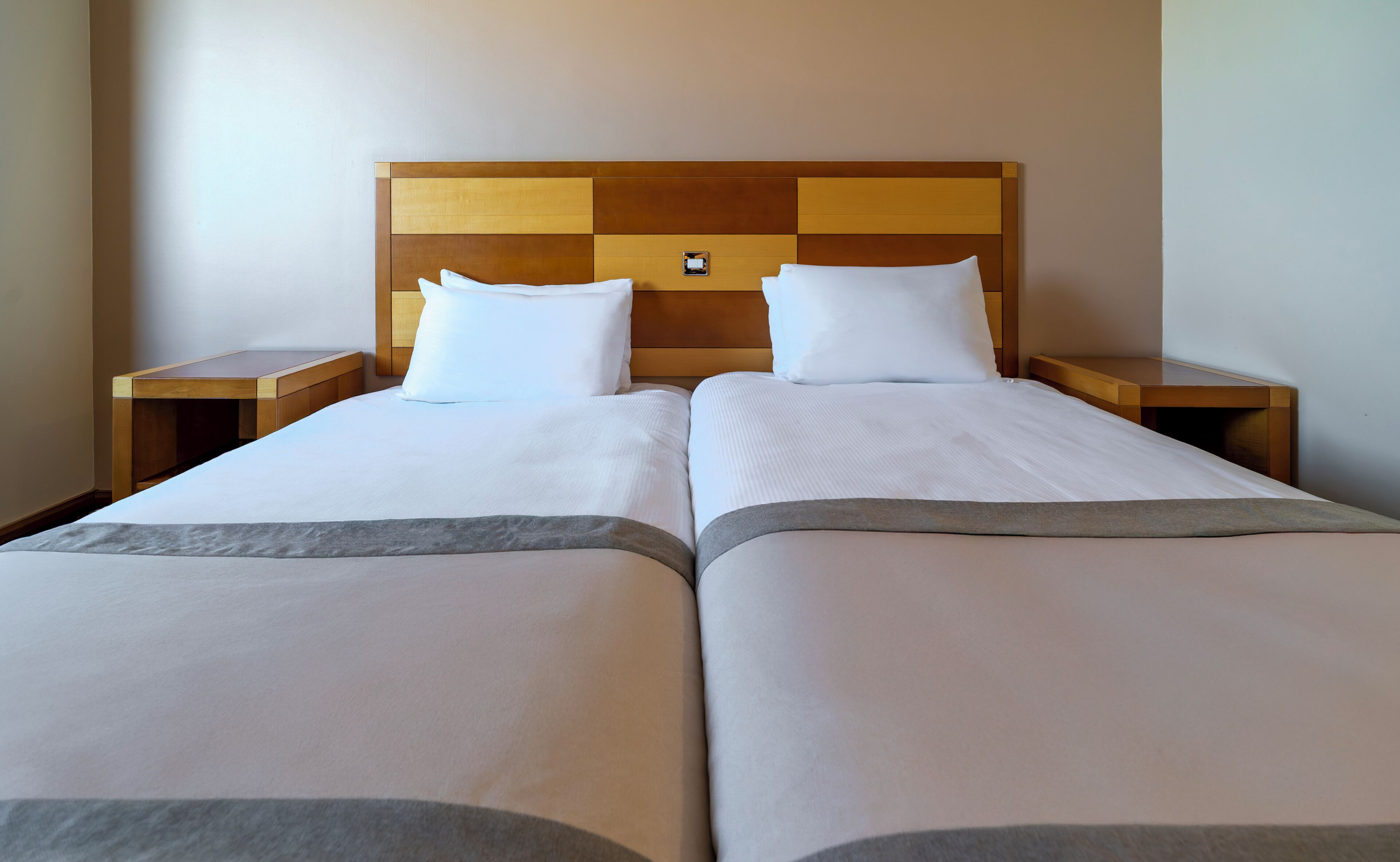 Ein Doppelbett mit Holz Kopfteil, zwei Kissen und einem Nachttisch.