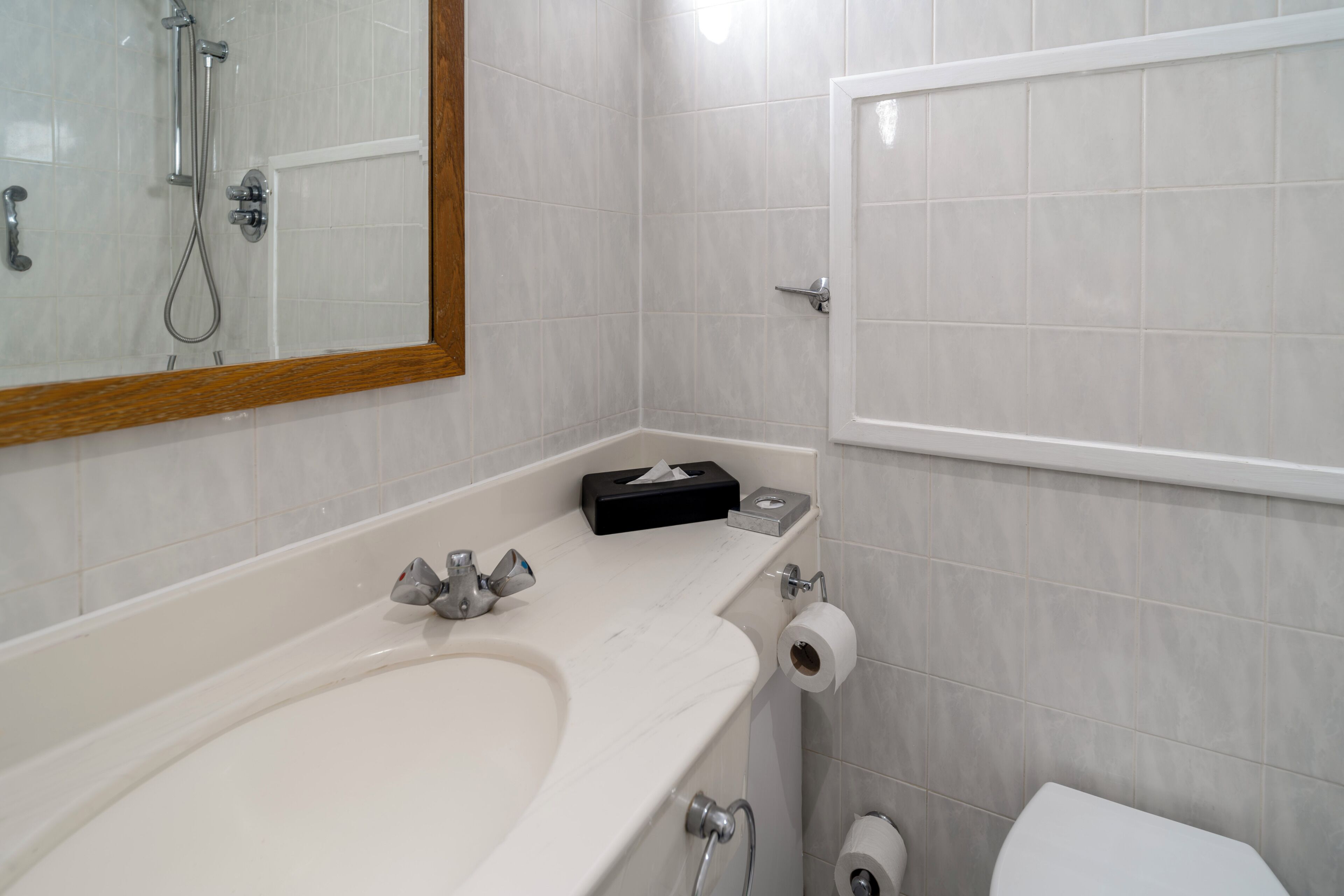 A bathroom with a sink, mirror, toilet, and shower.