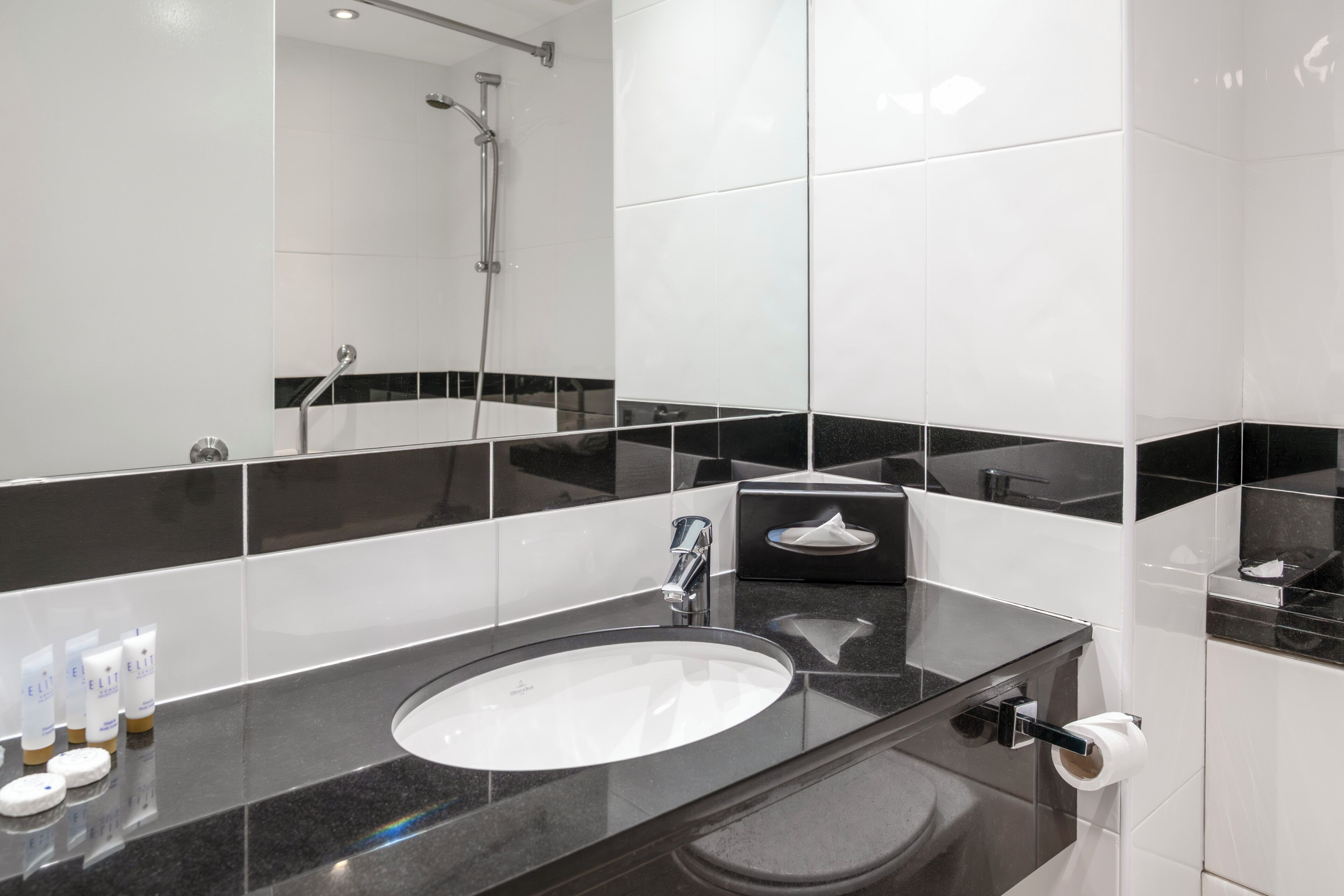 A modern bathroom with a large mirror, a sink, and a shower.