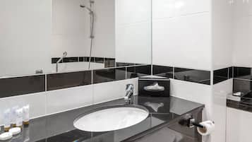 Un baño moderno con un espejo grande, un lavamanos y una ducha.